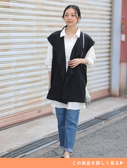 左肩にショルダーバッグを下げて、デニム×白シャツに黒いジレを合わせた女性