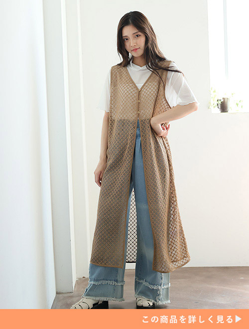 デニムに透け素材の白トップス、クロシェ風ジレを着た女性