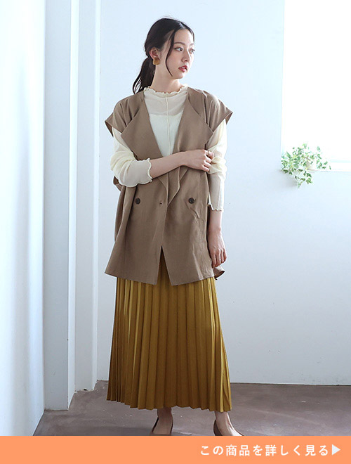 ベージュのジレとマスタードイエローのスカートを着た女性