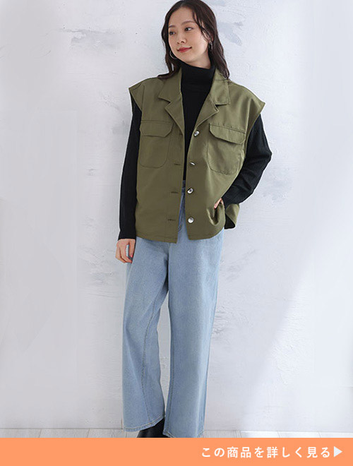 左手をポケット入れて右側を見るミリタリーカラーのジレを着た女性