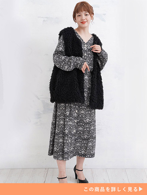 両手を上半身に添えてポーズを取る黒いボアジレを着た女性