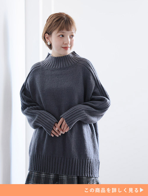 グレーのざっくりニットにチェックのボトムを合わせた女性