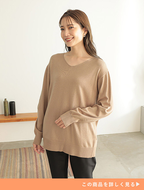 ベージュのニットに黒のパンツを着た女性