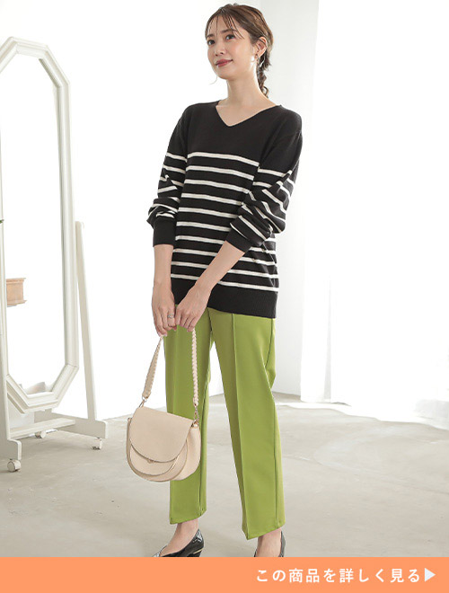 モノトーンのボーダーニットとグリーンのパンツを着た女性