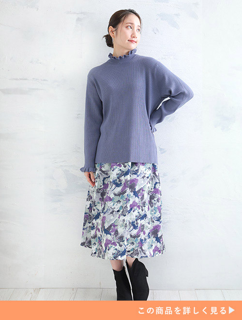 スモークブルーのリブニットと花柄プリントのスカートを履いた女性