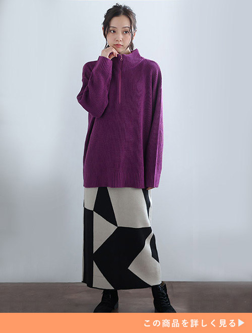 パープルのジップアップニットに柄スカートを履いた女性