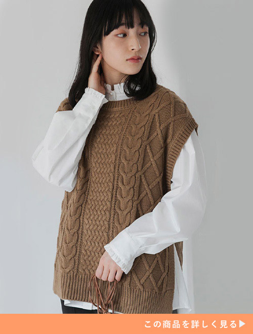 白シャツにブラウンのニットベストを着る女性