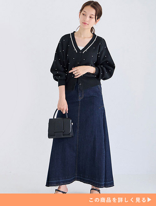 パールとビジューを使ったニットカーディガンにデニムのフレアスカートを着た女性