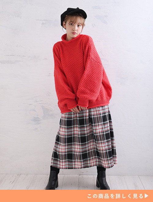 赤いニットにチェック柄スカートを履く女性