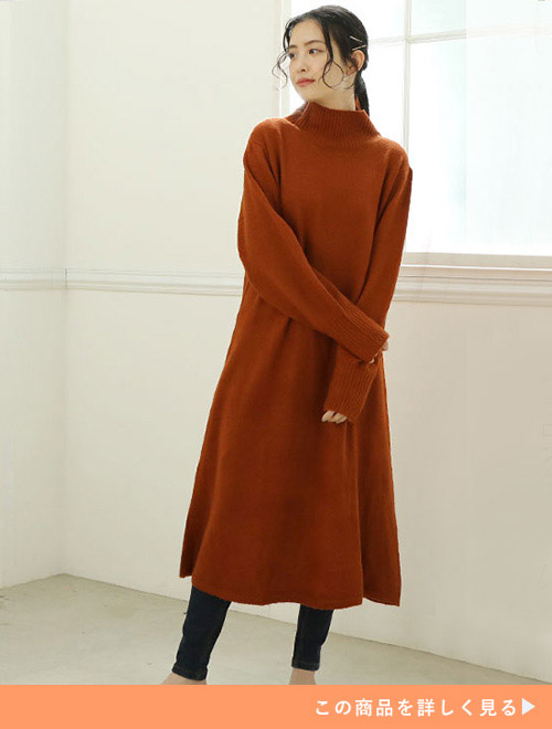 両手を前で組んで右を向く赤いロングニットワンピースを着た女性