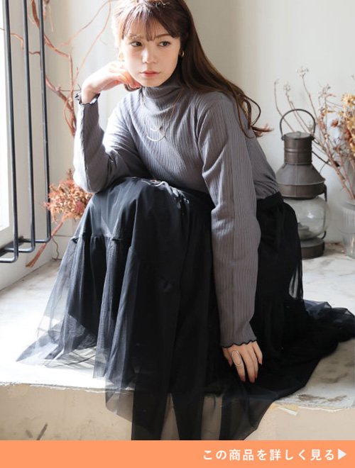 グレーのタートルネックニット×黒のチュールスカートを着る女性