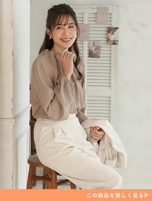 ベージュのブラウス×アイボリーのパンツを着る女性