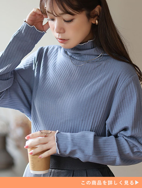 スモークブルーのボトルネックリブトップスを着る女性