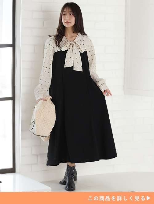 ドット柄のブラウスがドッキングした黒のワンピースを着る女性