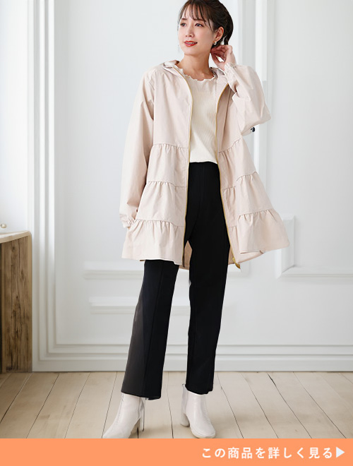 白トップス×黒パンツに、オフホワイトのティアードブルゾンを羽織る女性