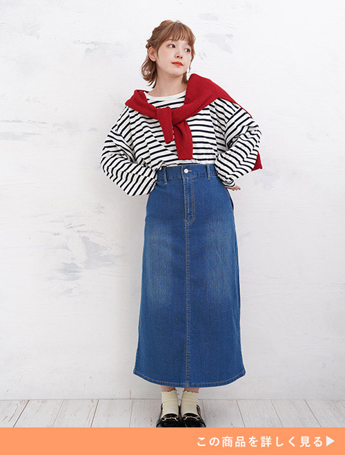白黒のボーダーTをデニムのタイトスカートにトップスインで着て、赤いトップスを肩に巻く女性