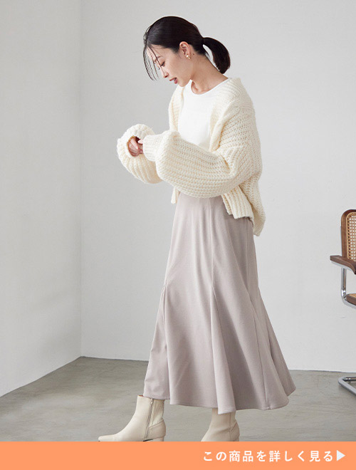 白系トップス×グレージュのタイトスカートに白ニットのカーディガンを羽織る女性