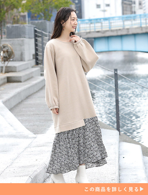 ベージュのロング丈スウェット×モノトーンの花柄スカートのドッキングワンピを着る女性。