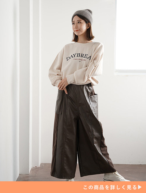 ベージュのスウェットを着て、ブラウンのエコレザーワイドパンツを履く女性