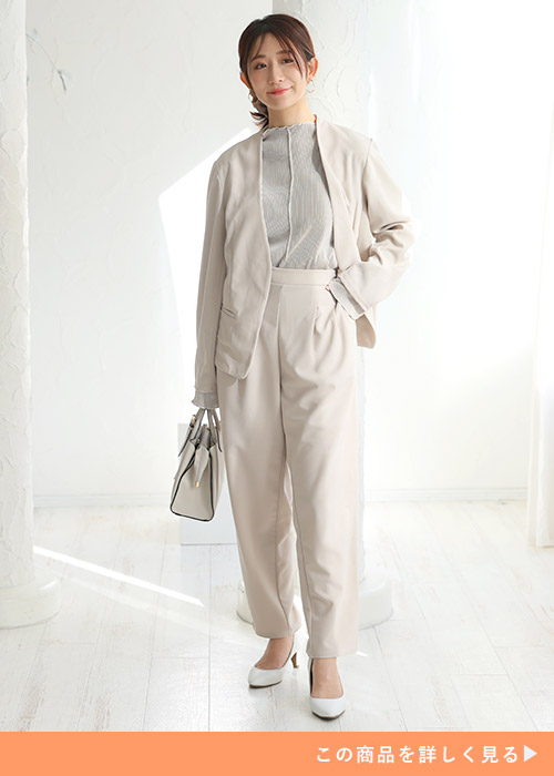 オフホワイトのジャケットを着て、オフホワイトのパンツを履く女性