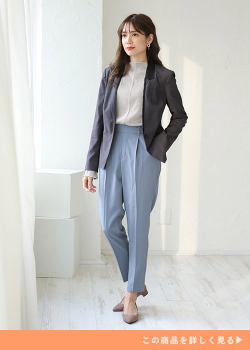 青いテーパードパンツをはいてジャケットを着た女性