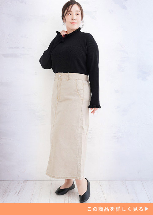 黒の長袖トップスをベージュのマキシ丈タイトスカートにインして着る女性