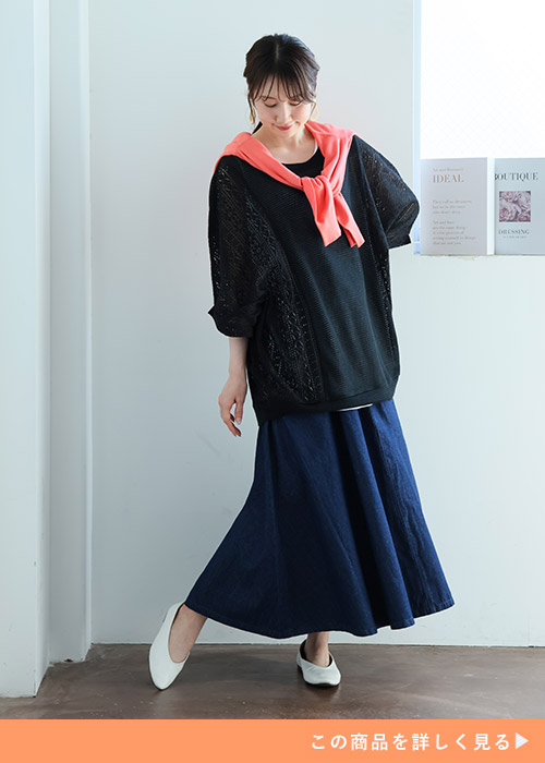 黒トップスを着て、インディゴデニムのフレアスカートを履く女性。