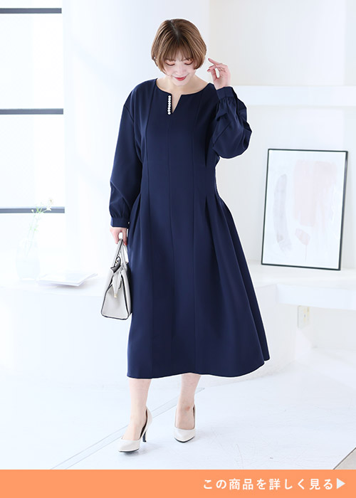 シンプルなネイビーのタック入りワンピースを着る女性