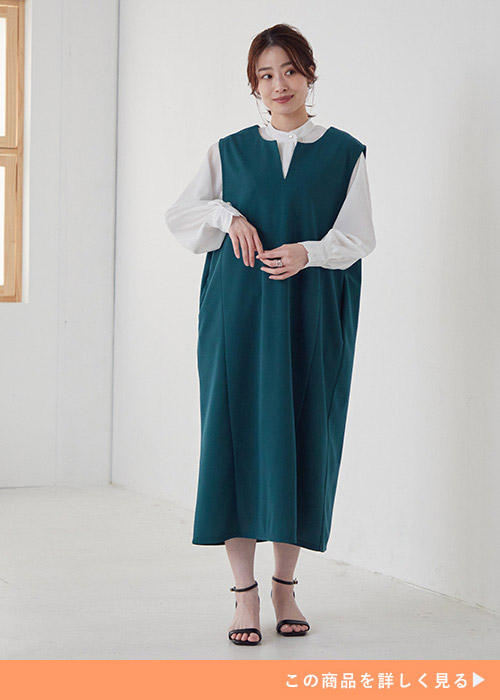 くすみグリーンのジャンスカに白のシャツブラウスをレイヤードして着る女性