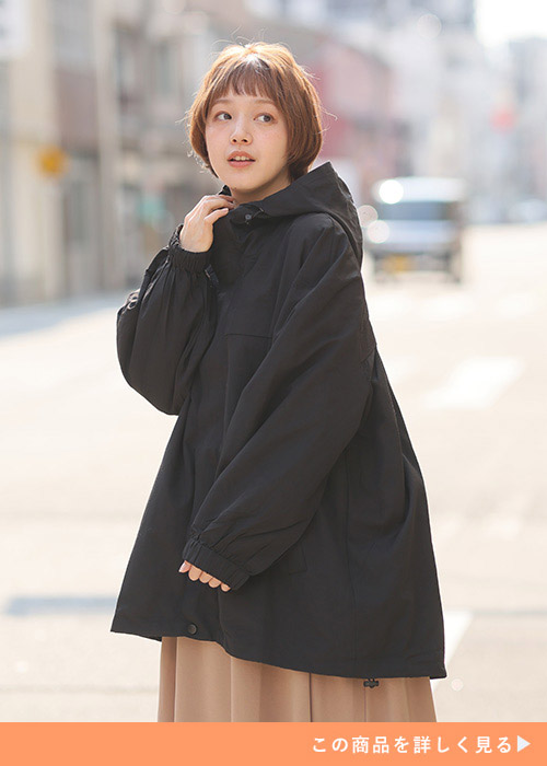 パーカの首元に右手を添えて左を見る女性