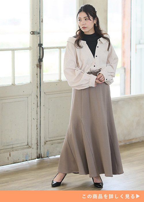 モカカラーのスカートにベージュのシャツ、インナーに黒トップスを合わせた女性