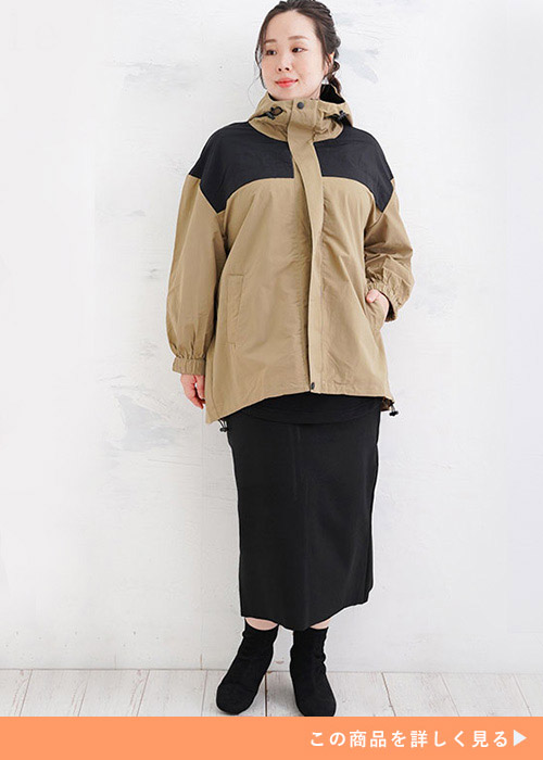 ベージュ×ブラックのマウンテンパーカに黒のタイトスカートを履く女性