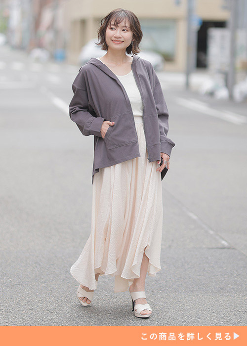 薄いベージュのスカートに白Tを着てモカブラウンのジップパーカを合わせた女性