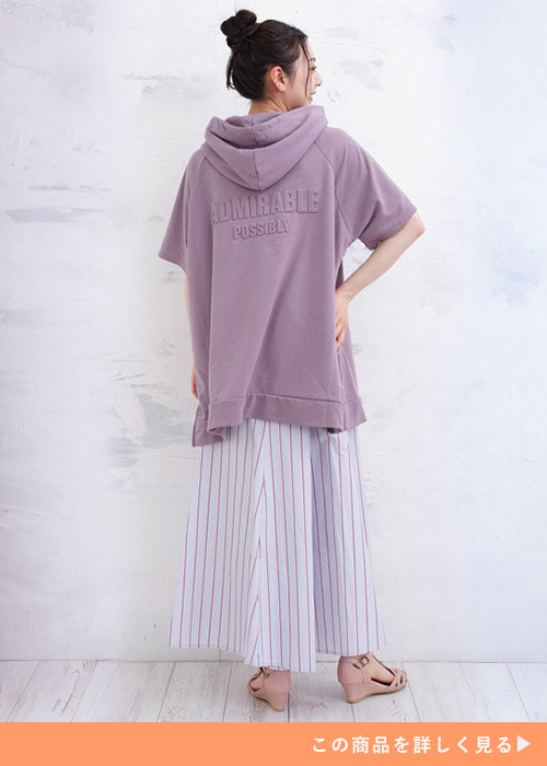 くすみパープルのパーカにストライプ柄のスカートを着た女性