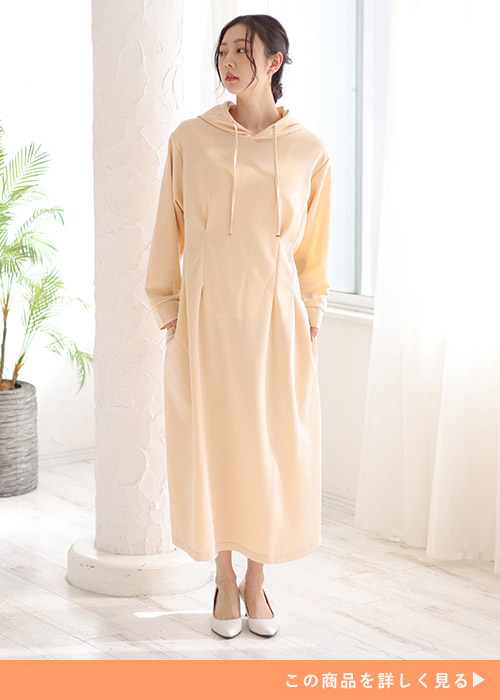 エクリュカラーのパーカワンピを着て右を向く女性