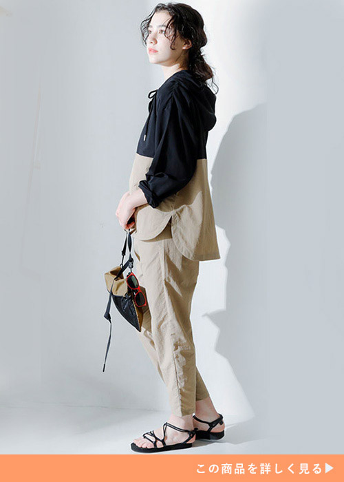 両手で鞄を持って身体を右に向けながら上を見る女性