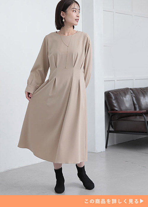ベージュのタックワンピースを着る女性
