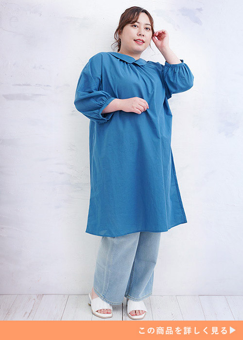 ブルーのチュニックブラウスを着て、下に薄色デニムを履く女性