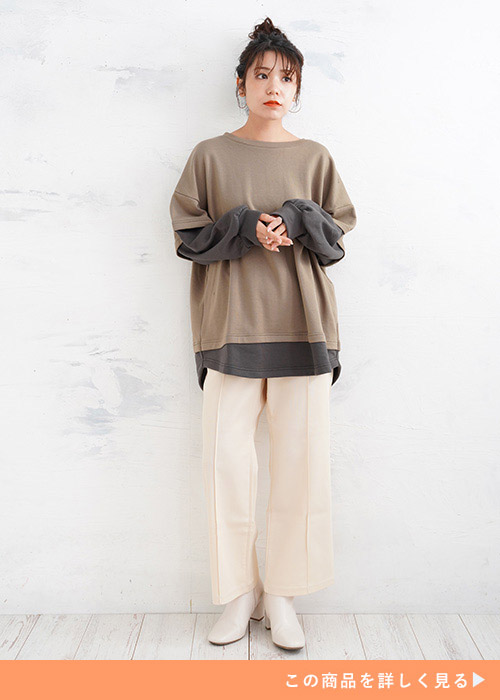 長袖Tに半袖Tを重ねたようなデザインのトップスに白のワイドパンツを履く女性