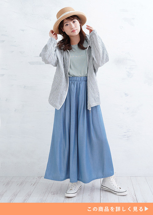 薄緑のトップス×水色のガウチョパンツにグレーのパーカを羽織る女性