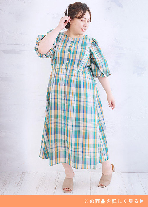 グリーンやオレンジのマドラスチェック柄ロングワンピースを着る女性