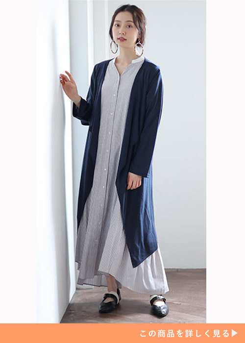 淡色のロング丈ワンピースを着て、ネイビーのロングカーディガンを羽織る女性