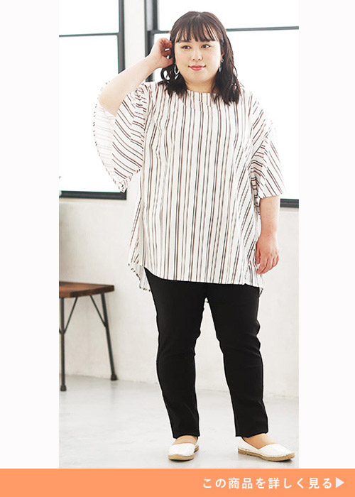 白地にボルドー色のストライプ柄チュニックトップスを着て黒のスキニーパンツを履く女性