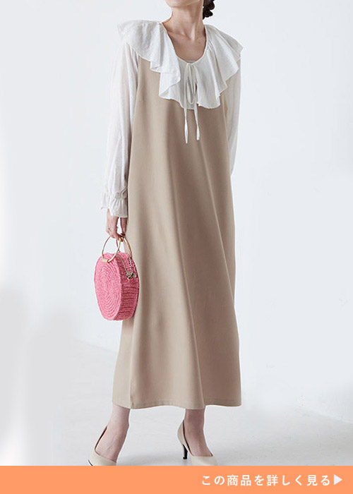 グレージュのIラインワンピに白のフリルブラウスを合わせて、右側を振り向く女性