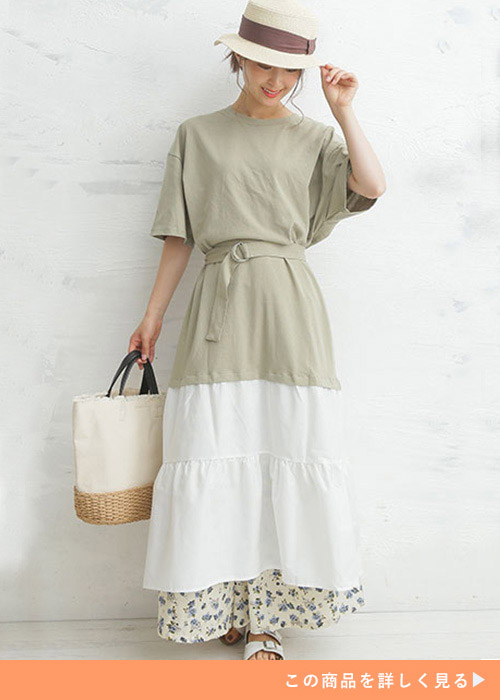 ベルト付きの白とカーキのワンピースに小花柄のスカートをレイヤードする女性