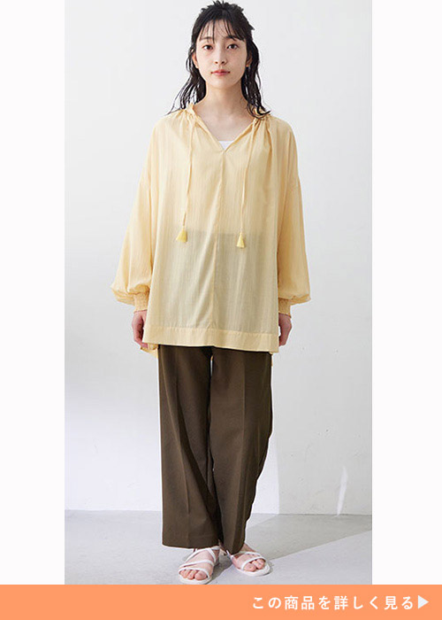 両手を両脇の下に下ろして前を見る女性