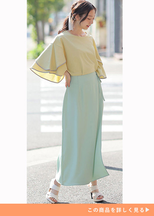 ミントカラーのスカートに黄色の袖フレアトップスを合わせた女性