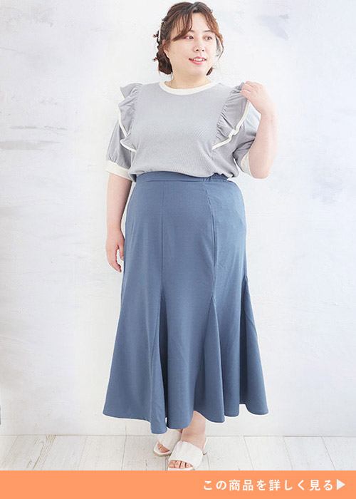 ブルーのマーメイドスカートにくすみブルーのフレアトップスを合わせた女性