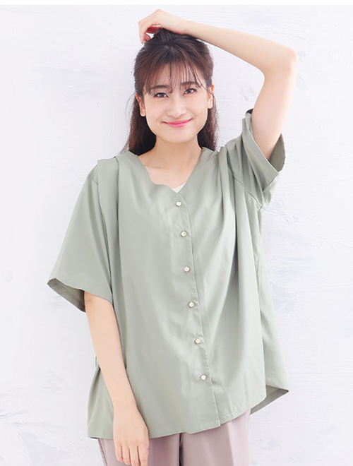 グリーンの肩タックブラウスにくすみカラーのパンツを履く女性