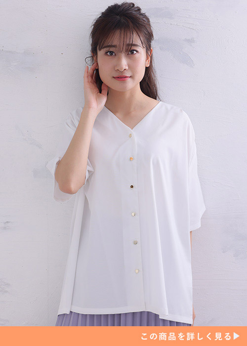 Vネックの白シャツに薄いパープルのプリーツスカートを履く女性